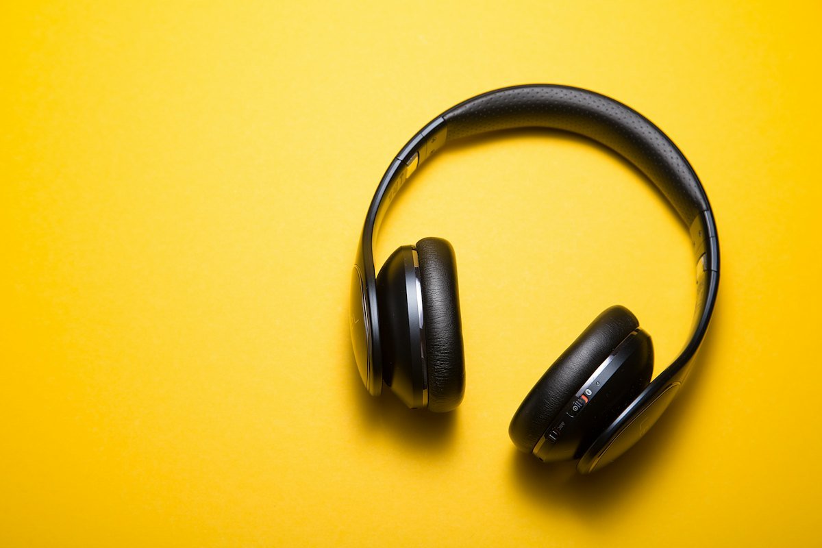 Black over-ear headphones lying on a bright yellow background